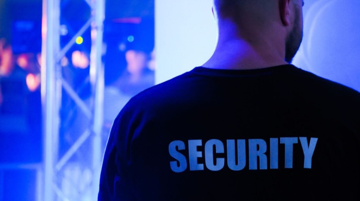 A security guard wearing a black shirt in a dimly lit nightclub.