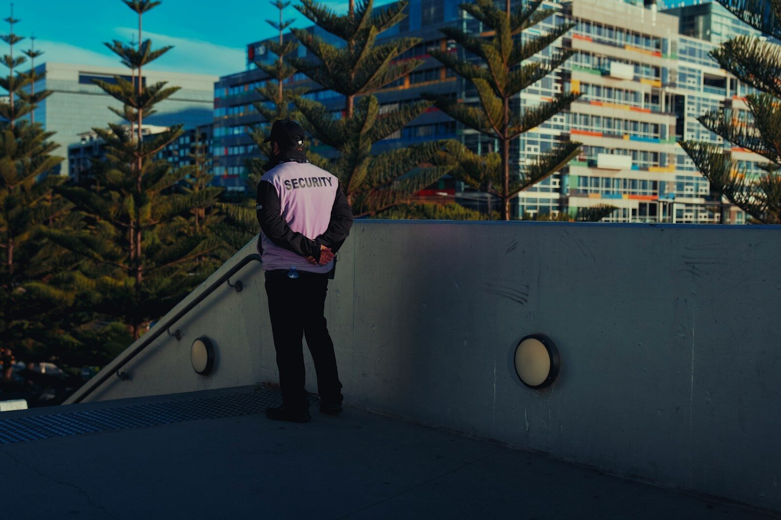 Security guard on concrete walkway overlooking modern buildings