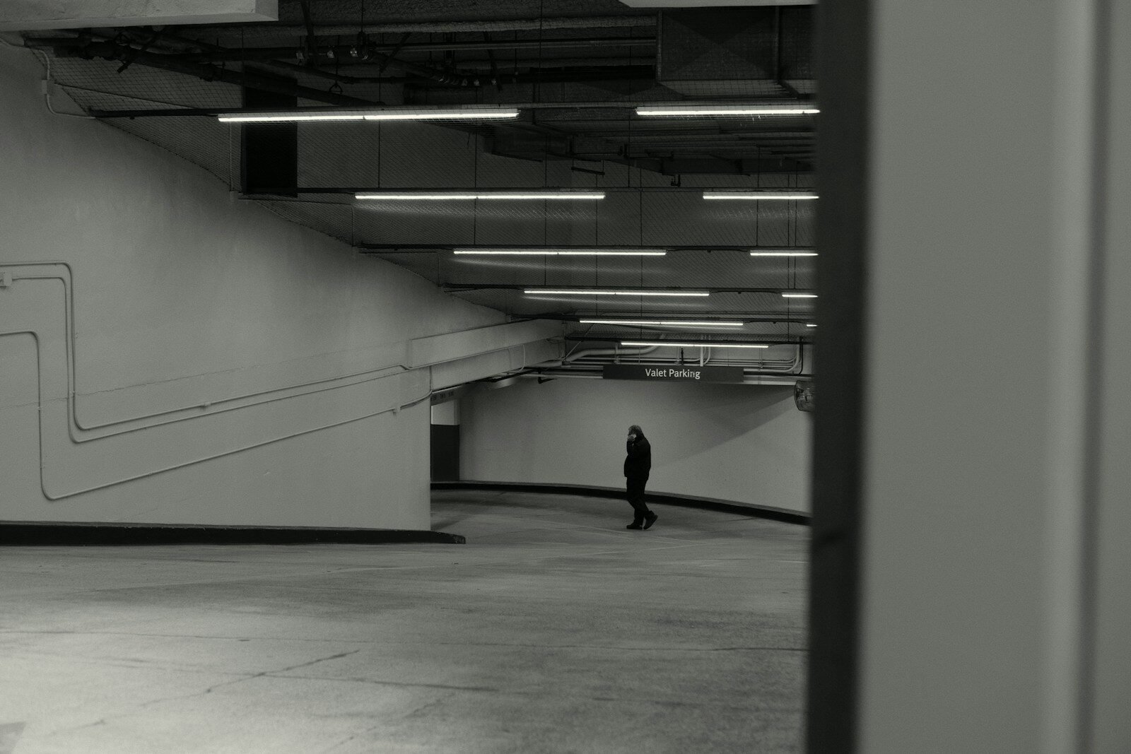 A lone person stands in a dimly lit underground walkway