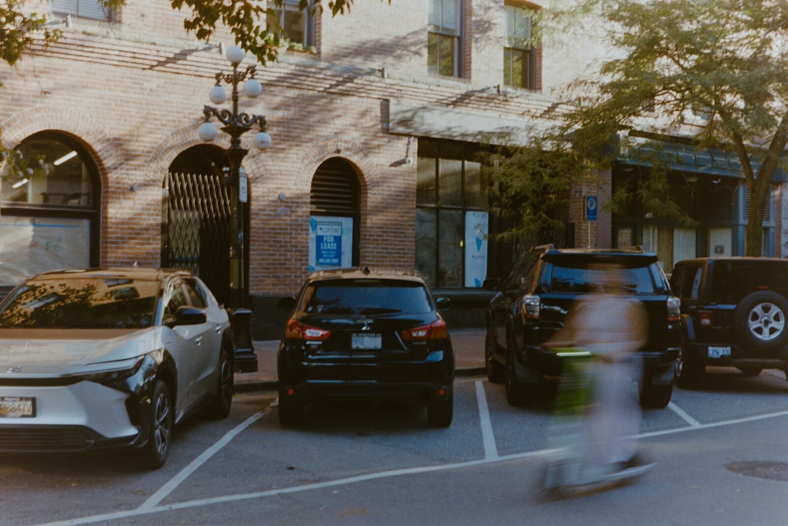 Cars parked on street with blurry person on scooter